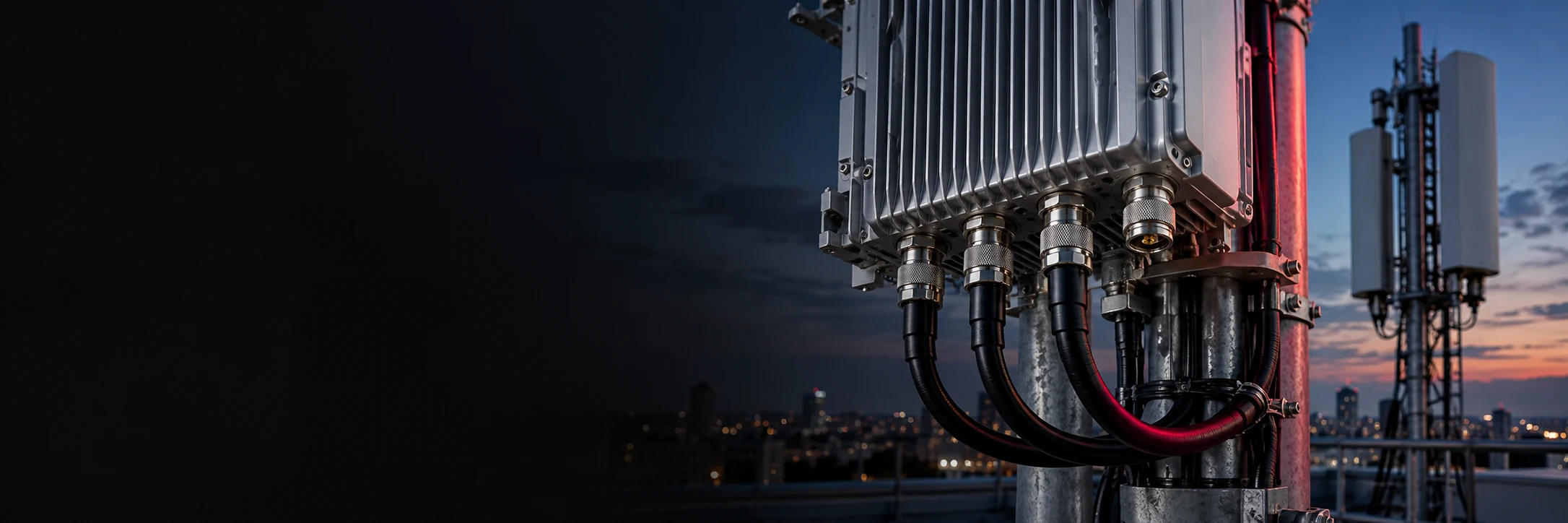 Coaxial RF cables connected to a radio unit with a telecom antenna in the background